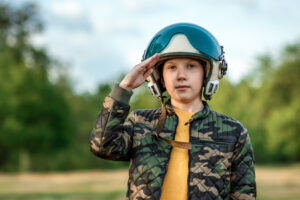 Мальчик в шлеме летчика отдает честь